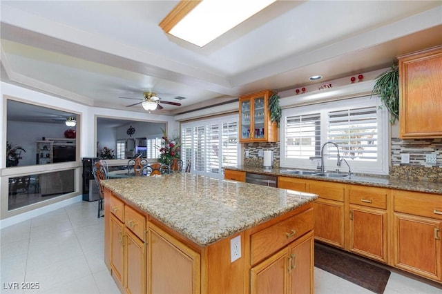 kitchen featuring glass insert cabinets, a center island, a sink, and backsplash