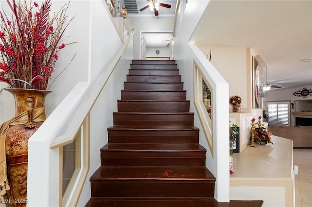 stairs featuring ceiling fan, visible vents, and crown molding