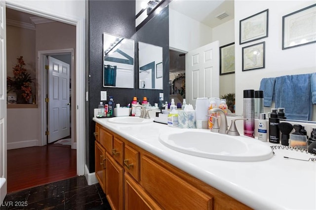 bathroom featuring visible vents, a sink, baseboards, and double vanity