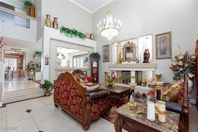 living area with a glass covered fireplace, an inviting chandelier, a high ceiling, crown molding, and light tile patterned flooring