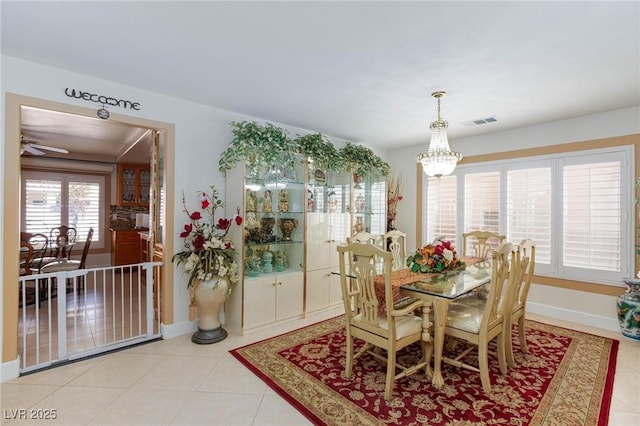 dining area featuring light tile patterned floors, ceiling fan with notable chandelier, visible vents, and baseboards