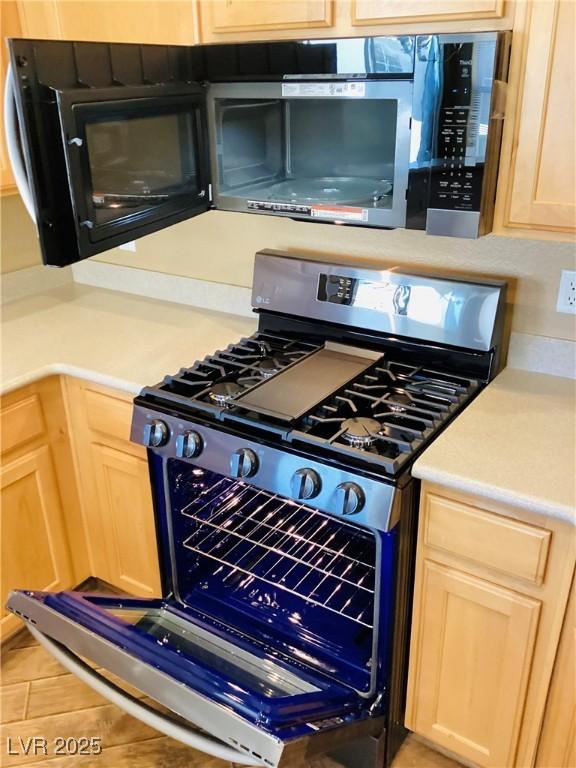 kitchen with stainless steel appliances, light countertops, and light brown cabinetry