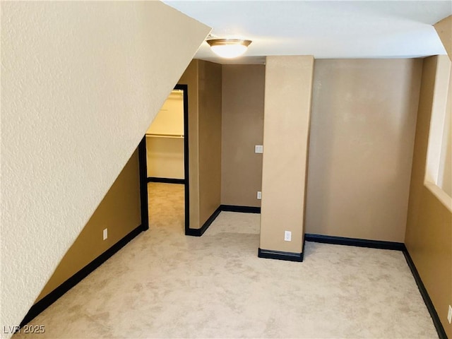 bonus room with baseboards and light colored carpet