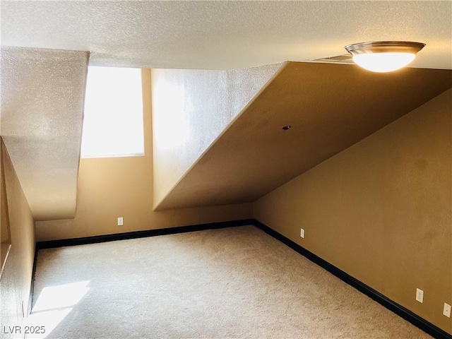 additional living space with a textured ceiling, carpet flooring, and baseboards