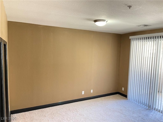 unfurnished room featuring carpet, visible vents, a textured ceiling, and baseboards