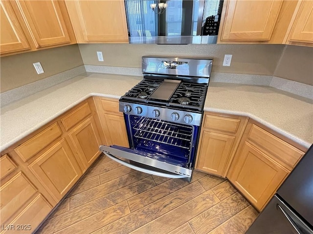 kitchen featuring light brown cabinets, stainless steel appliances, light countertops, and wood tiled floor