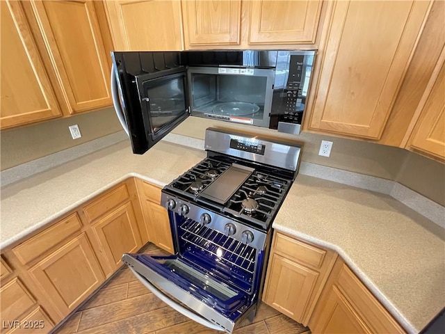 kitchen featuring gas stove, light countertops, and light brown cabinets