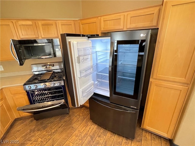 kitchen featuring light wood-style flooring, appliances with stainless steel finishes, light countertops, and light brown cabinetry