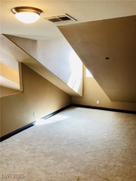 bonus room featuring lofted ceiling, a textured ceiling, visible vents, and carpet flooring