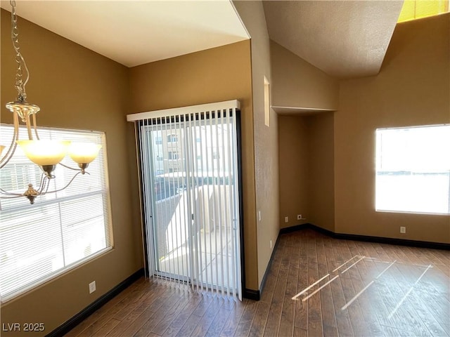 interior space with dark wood-style floors, vaulted ceiling, plenty of natural light, and baseboards