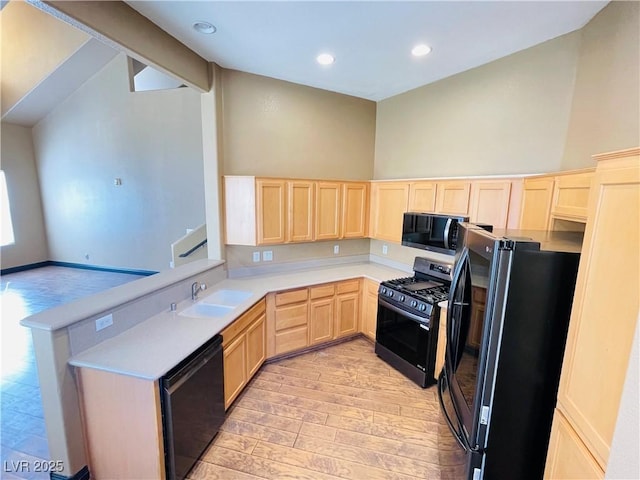 kitchen with light wood-style flooring, light countertops, black appliances, light brown cabinets, and a sink