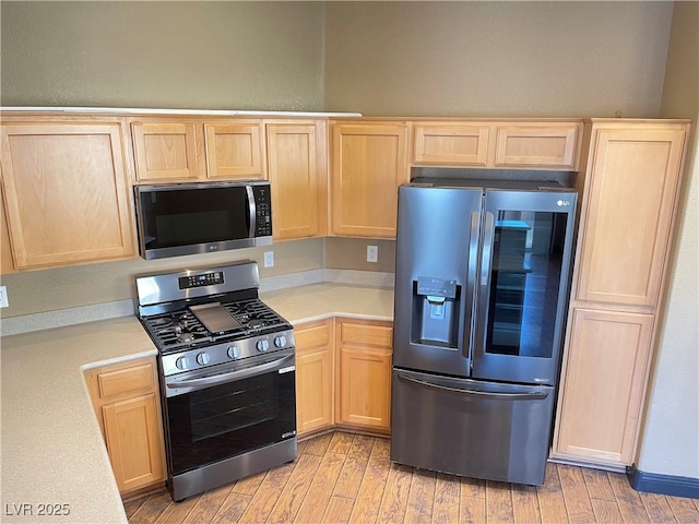 kitchen with stainless steel appliances, light countertops, and light brown cabinetry