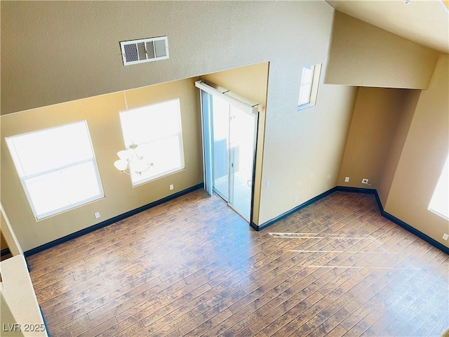 bonus room with a chandelier, hardwood / wood-style flooring, visible vents, and baseboards