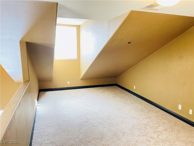 bonus room featuring lofted ceiling, carpet, and baseboards