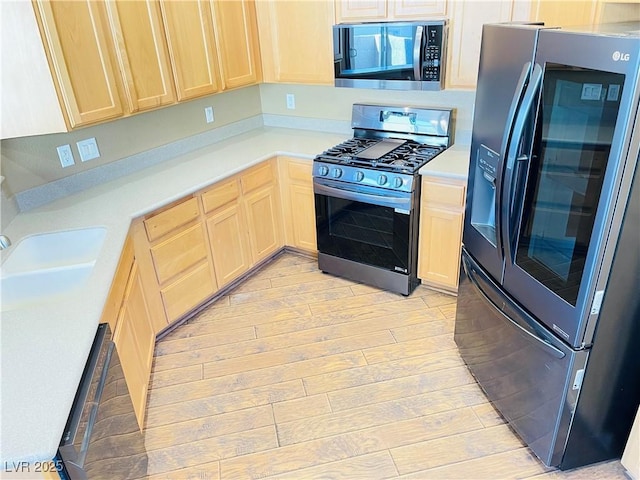 kitchen with stainless steel appliances, light countertops, light wood-style flooring, and light brown cabinetry