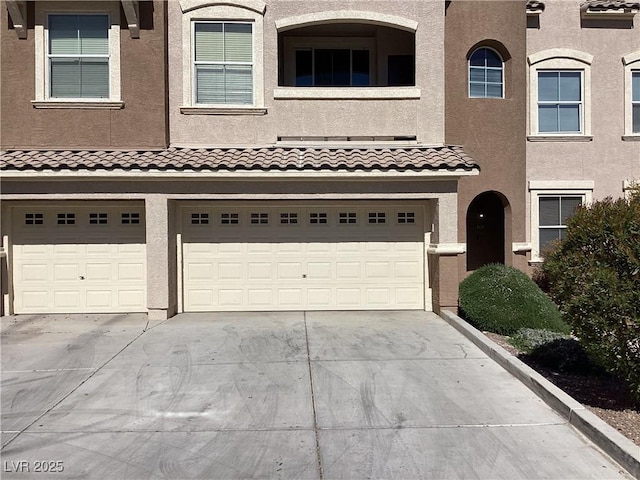 view of front of house featuring an attached garage, concrete driveway, and stucco siding