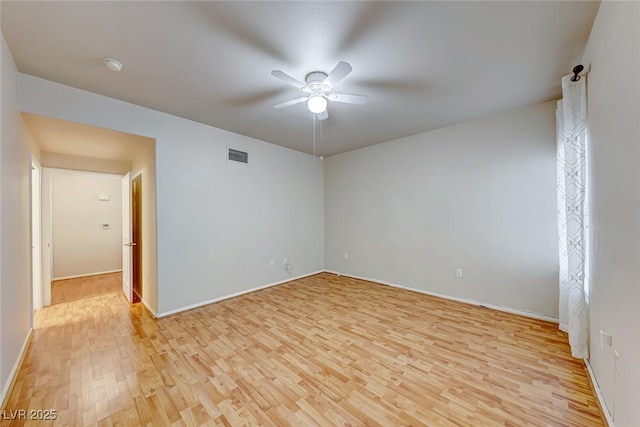 empty room with a ceiling fan, light wood-type flooring, visible vents, and baseboards