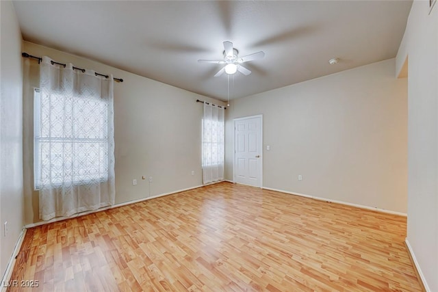 empty room featuring light wood-type flooring, baseboards, and a ceiling fan