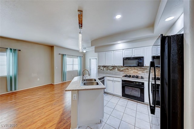 kitchen featuring a sink, white cabinetry, light countertops, black appliances, and decorative light fixtures