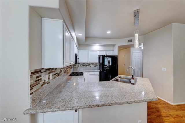 kitchen featuring hanging light fixtures, white cabinets, a sink, a peninsula, and black appliances