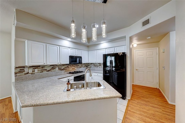 kitchen with decorative light fixtures, light countertops, white cabinets, a sink, and black appliances