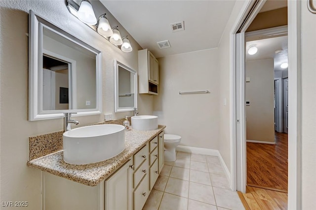 full bathroom with visible vents, toilet, a sink, baseboards, and tile patterned floors