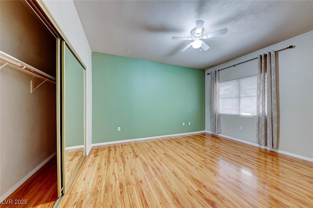 unfurnished bedroom with light wood-type flooring, a closet, ceiling fan, and baseboards