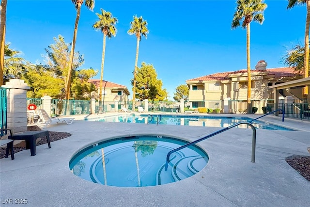 pool with fence, a community hot tub, and a patio