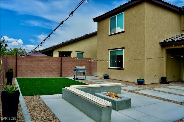 rear view of property featuring a fenced backyard, a patio, and stucco siding