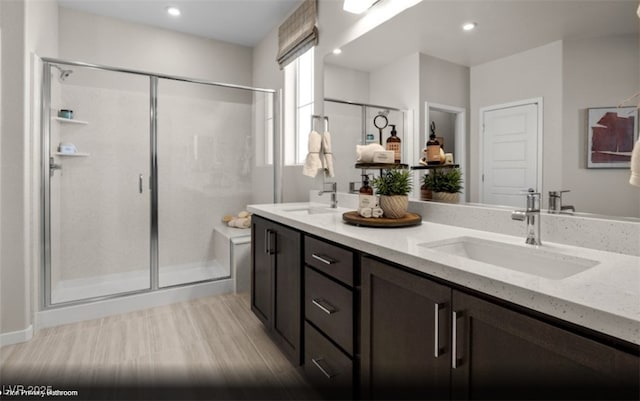 full bath with double vanity, a shower stall, a sink, and recessed lighting