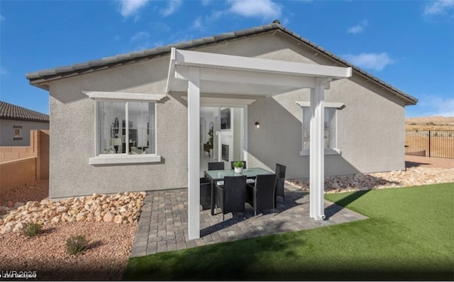 rear view of property with a patio, fence, a tiled roof, a lawn, and stucco siding