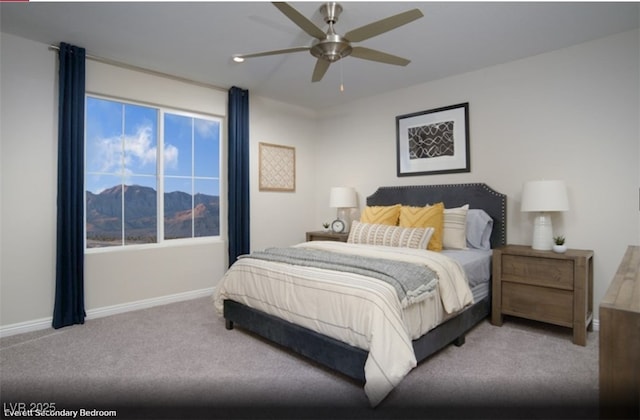 carpeted bedroom featuring ceiling fan, a mountain view, and baseboards