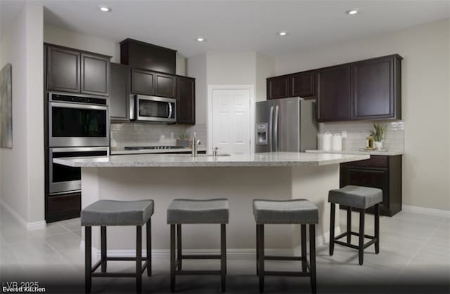 kitchen featuring stainless steel appliances, a breakfast bar, a sink, and a kitchen island with sink