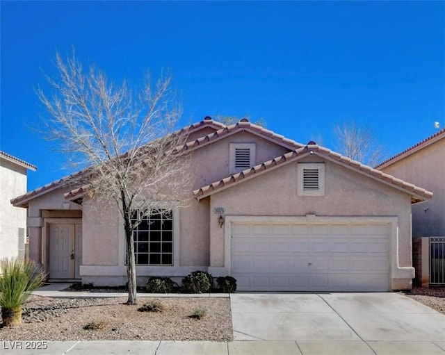 mediterranean / spanish home featuring concrete driveway, an attached garage, a tile roof, and stucco siding