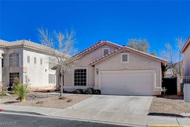 view of front of property with a garage, a tiled roof, concrete driveway, and stucco siding