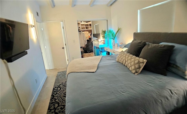 bedroom featuring a closet, a walk in closet, and beam ceiling