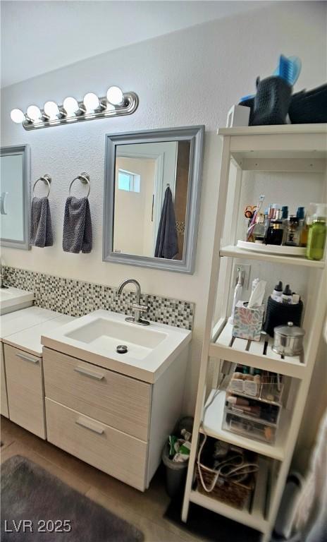 bathroom featuring double vanity, backsplash, and a sink