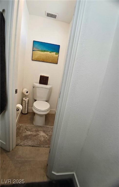 bathroom with tile patterned flooring, baseboards, visible vents, and toilet