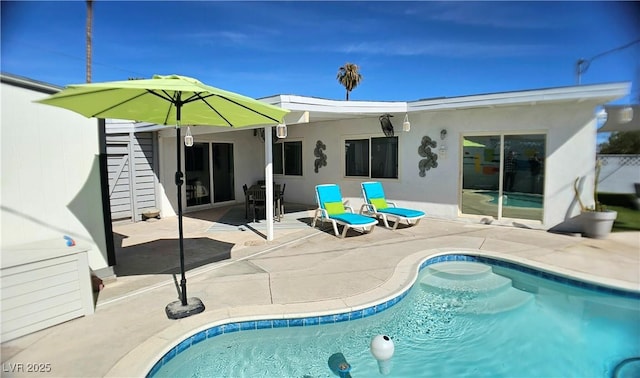 back of property with an outdoor pool, a patio, and stucco siding