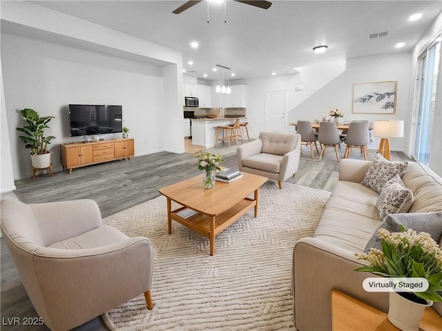 living room with light wood-style floors, ceiling fan, visible vents, and recessed lighting