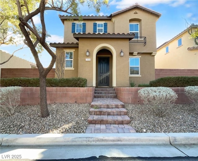 mediterranean / spanish home featuring a tiled roof, fence, and stucco siding