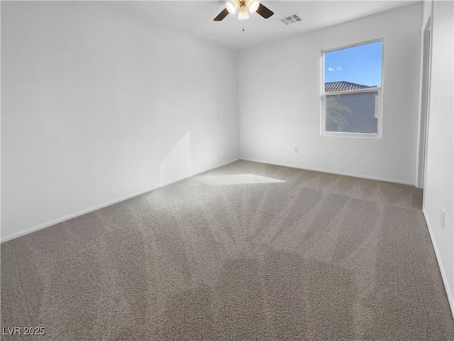 carpeted spare room featuring ceiling fan, visible vents, and baseboards