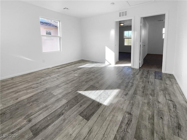 unfurnished room featuring baseboards, visible vents, and wood finished floors