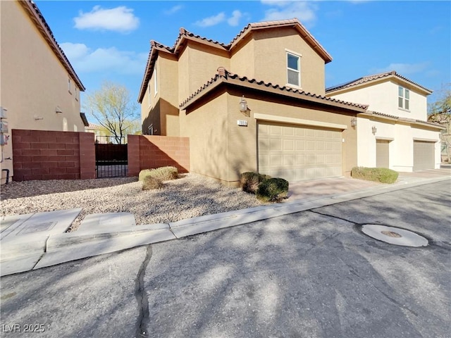 view of front of home featuring an attached garage, fence, a tile roof, concrete driveway, and stucco siding