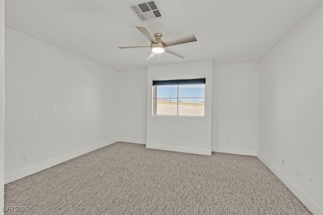 carpeted empty room with baseboards, visible vents, and a ceiling fan