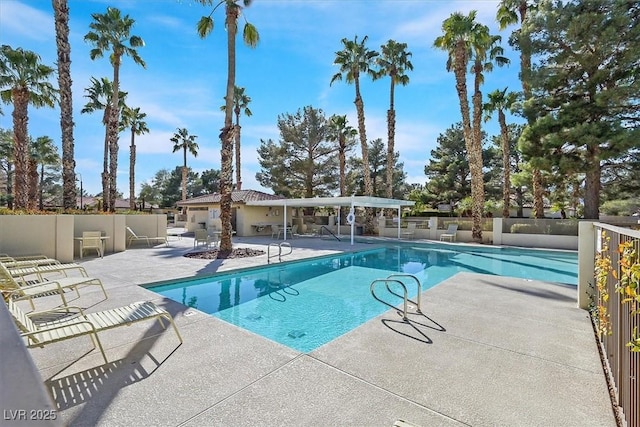 pool with a patio area and fence