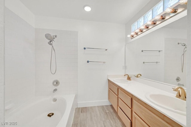 bathroom with double vanity, bathtub / shower combination, a sink, and wood finished floors