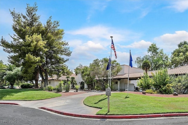 exterior space with driveway, a front lawn, a tiled roof, and stucco siding