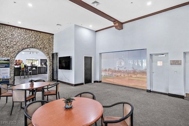 dining area with arched walkways, carpet, visible vents, a towering ceiling, and beamed ceiling