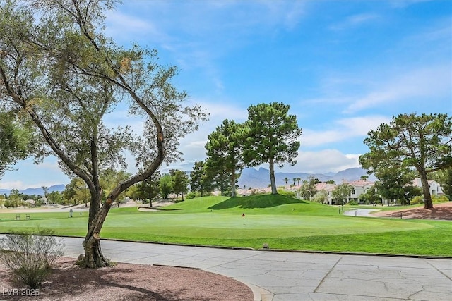 surrounding community featuring view of golf course, a mountain view, and a lawn